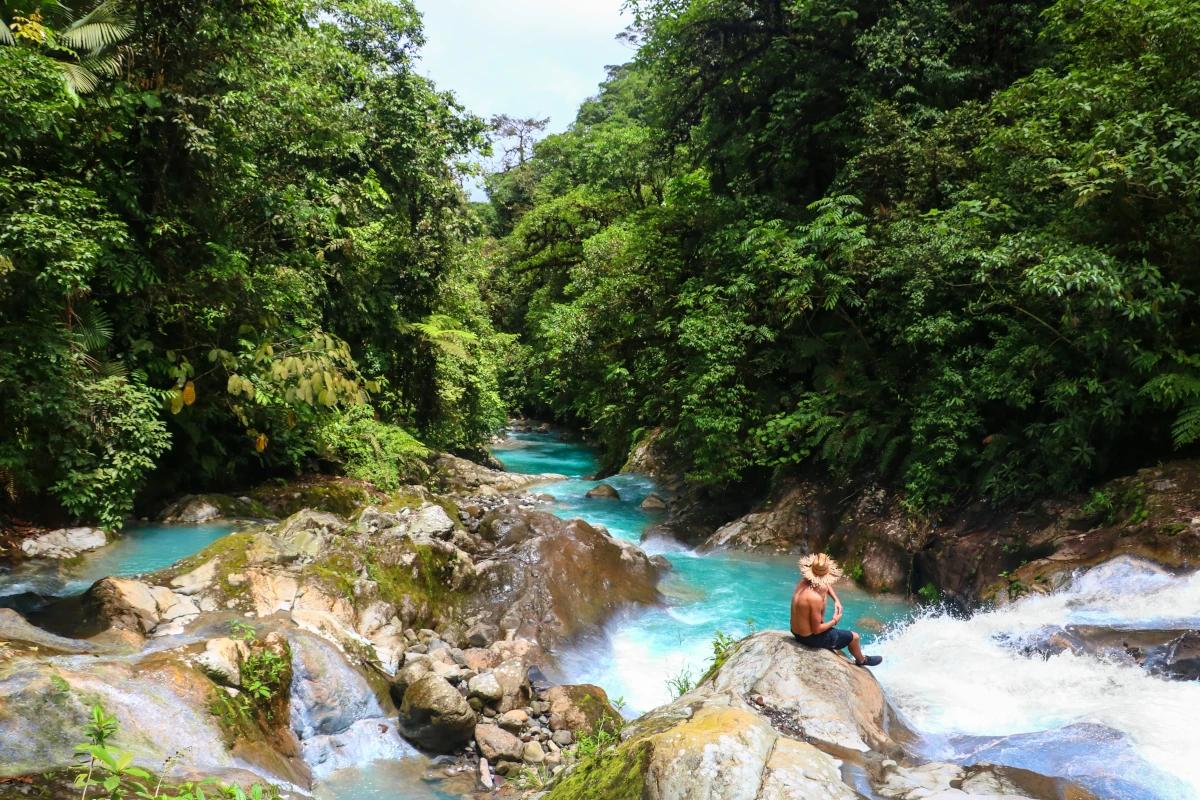 The Quebrada Gata River, characterized by its blue and clear waters, meanders through lush tropical vegetation